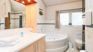 Et stilfuldt badeværelse med et stort spejl, badekar, toilet og håndvask.