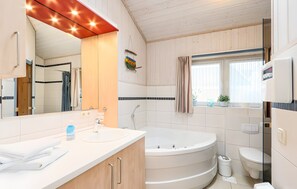 A modern bathroom with a large mirror, a bathtub, a toilet, and a sink. - Holiday Home '55 Typ Eisvogel' with Private Terrace, Private Garden and Wi-Fi (Rechlin)
