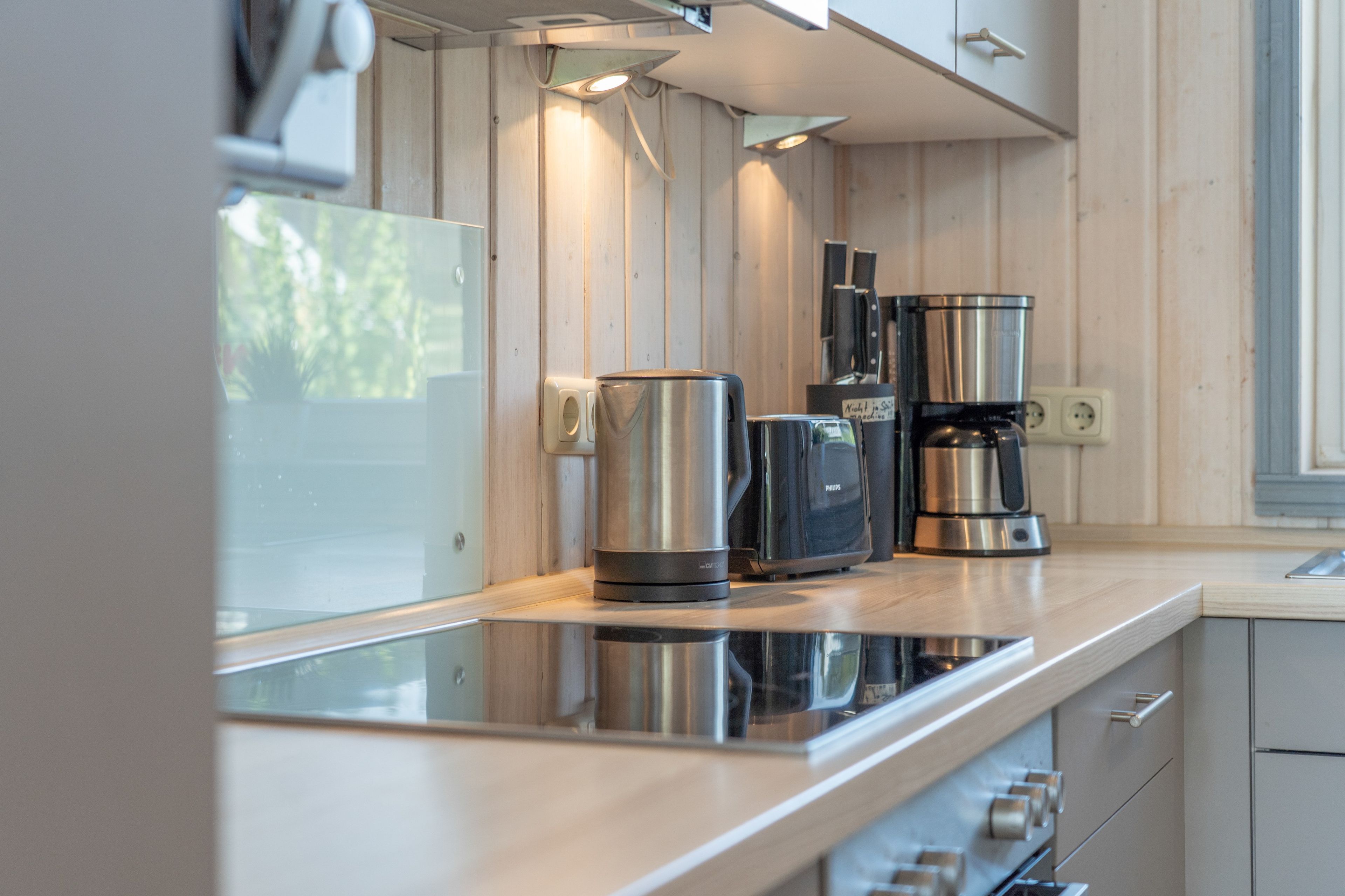 Una cocina moderna con electrodomésticos de acero inoxidable, armarios de madera y encimera de vidrio.