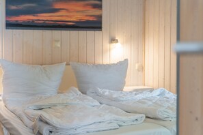 A bed with white bedding, a nightstand, and a wall-mounted lamp. - Holiday Home '55 Typ Eisvogel' with Private Terrace, Private Garden and Wi-Fi (Rechlin)