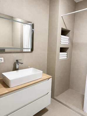A modern bathroom with a rectangular sink, a mirror, and a shower area. - Vrbo Property (Chișinău)