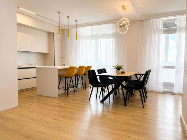 A modern kitchen with a central island, bar stools, and a dining table with chairs. - Vrbo Property (Chișinău)