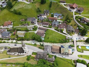 Een vogelvluchtperspectief van een woonwijk met huizen, straten en een kerk.