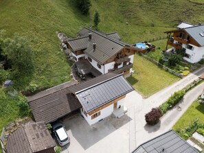 Een huis met twee verdiepingen, een garage, een zwembad en een verzorgd gazon.