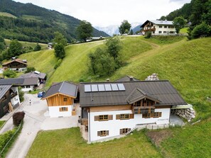 Een bergdorpszicht met traditionele houten huizen, een geasfalteerde oprit en een helder uitzicht op de omliggende heuvels.