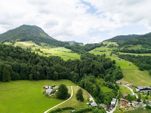 Un paysage rural caractérisé par des collines douces, des maisons dispersées et de vastes forêts.