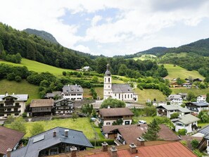 Ein Dorf mit traditioneller Architektur, eine Kirche mit Glockenturm und Häuser mit geneigten Dächern.