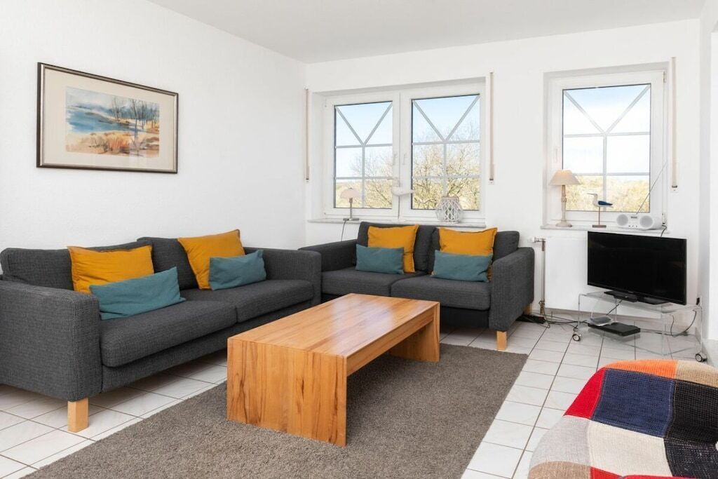 Una sala de estar moderna con un sofá modular, una mesa de centro de madera y un televisor sobre un mueble.