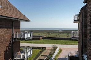 A residential building with a view of a flat landscape and a body of water in the distance. - Holiday apartment in Juist with swimming pool (Juist)