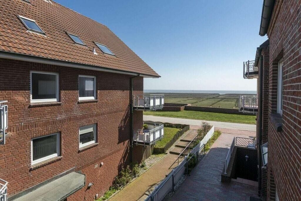 Een meerhoog gebouw van baksteen met een plat dak, meerdere ramen en een klein buitengebied met een pad.