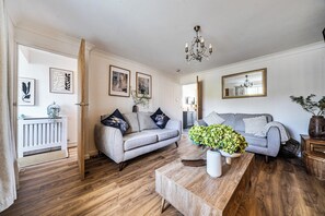 Ein Wohnzimmer mit grauem Sofa, einem Holztisch und einem Spiegel an der Wand.