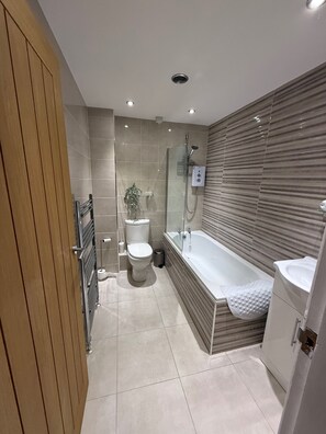 A modern bathroom with a shower, toilet, and bathtub. - House Sleeps 4 With Parking and Garden (Scunthorpe)