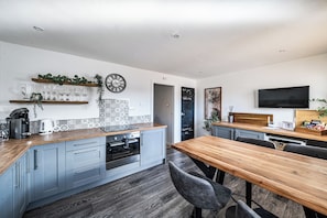 A modern kitchen with a wooden countertop, built-in appliances, and a dining area with a wooden table and chairs. - House Sleeps 4 With Parking and Garden (Scunthorpe)