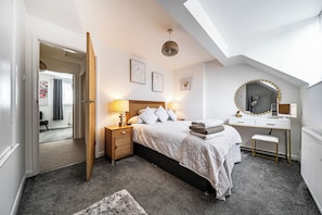 A bedroom with a bed, bedside tables, a desk, a mirror, and artwork on the walls. - House Sleeps 4 With Parking and Garden (Scunthorpe)