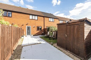 A residential property with a brick house, a wooden fence, a paved driveway, and a small garden area. - House Sleeps 4 With Parking and Garden (Scunthorpe)