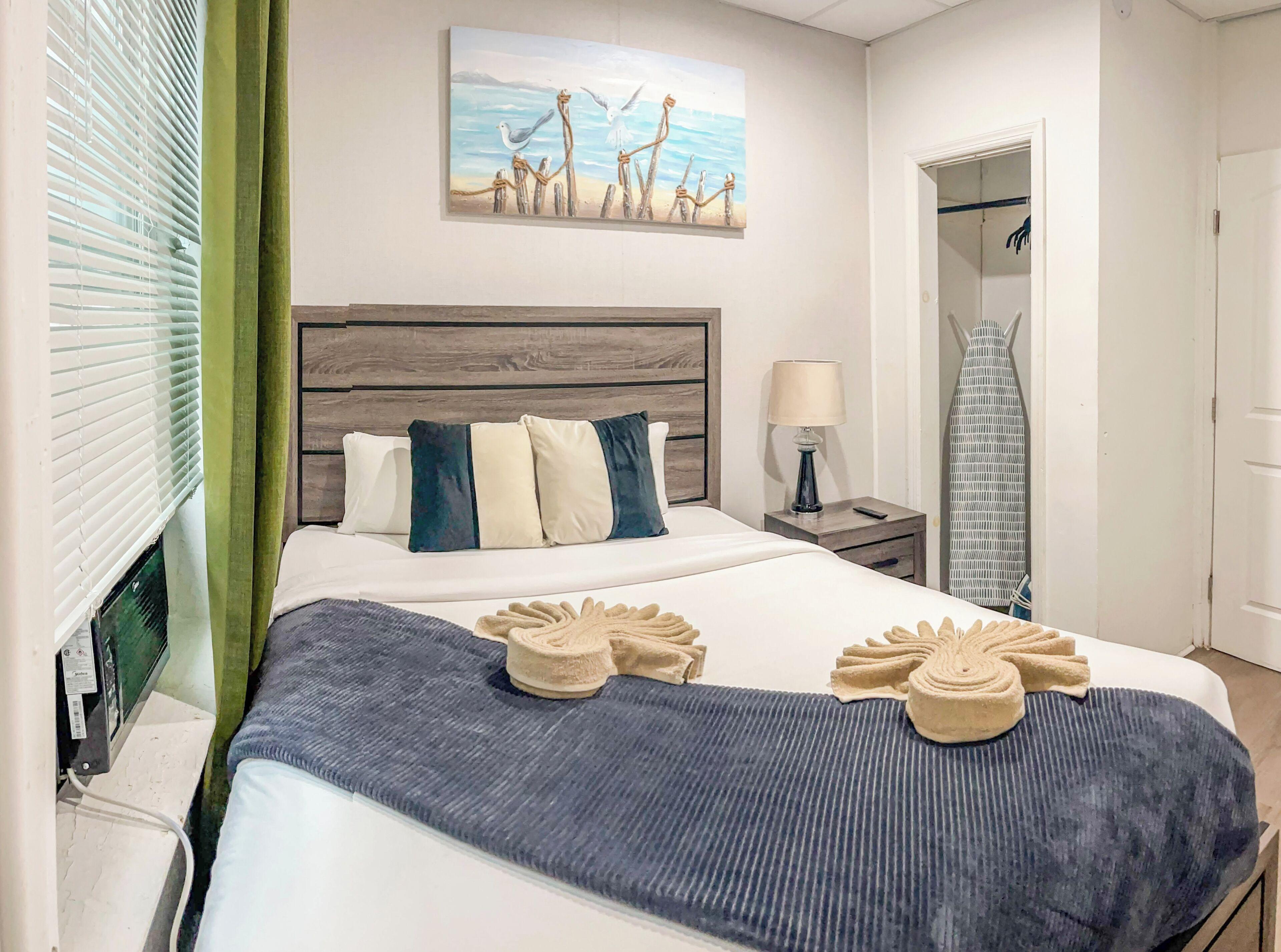 Ein Hotelzimmer mit Bett, Gemälde, Nachttisch und Kleiderschrank.