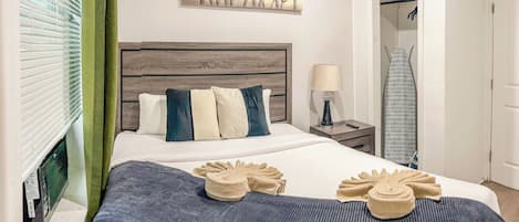 Una habitación de hotel con una cama, un cuadro, una mesita de noche y un armario.