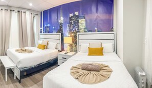 Une chambre d’hôtel avec deux lits, une table de chevet, une lampe et une vue sur le paysage urbain.
