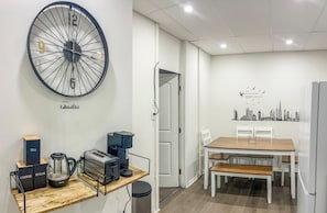 Une cuisine moderne avec une grande horloge, une machine à café, un grille-pain et une bouilloire posés sur un plan de travail en bois.