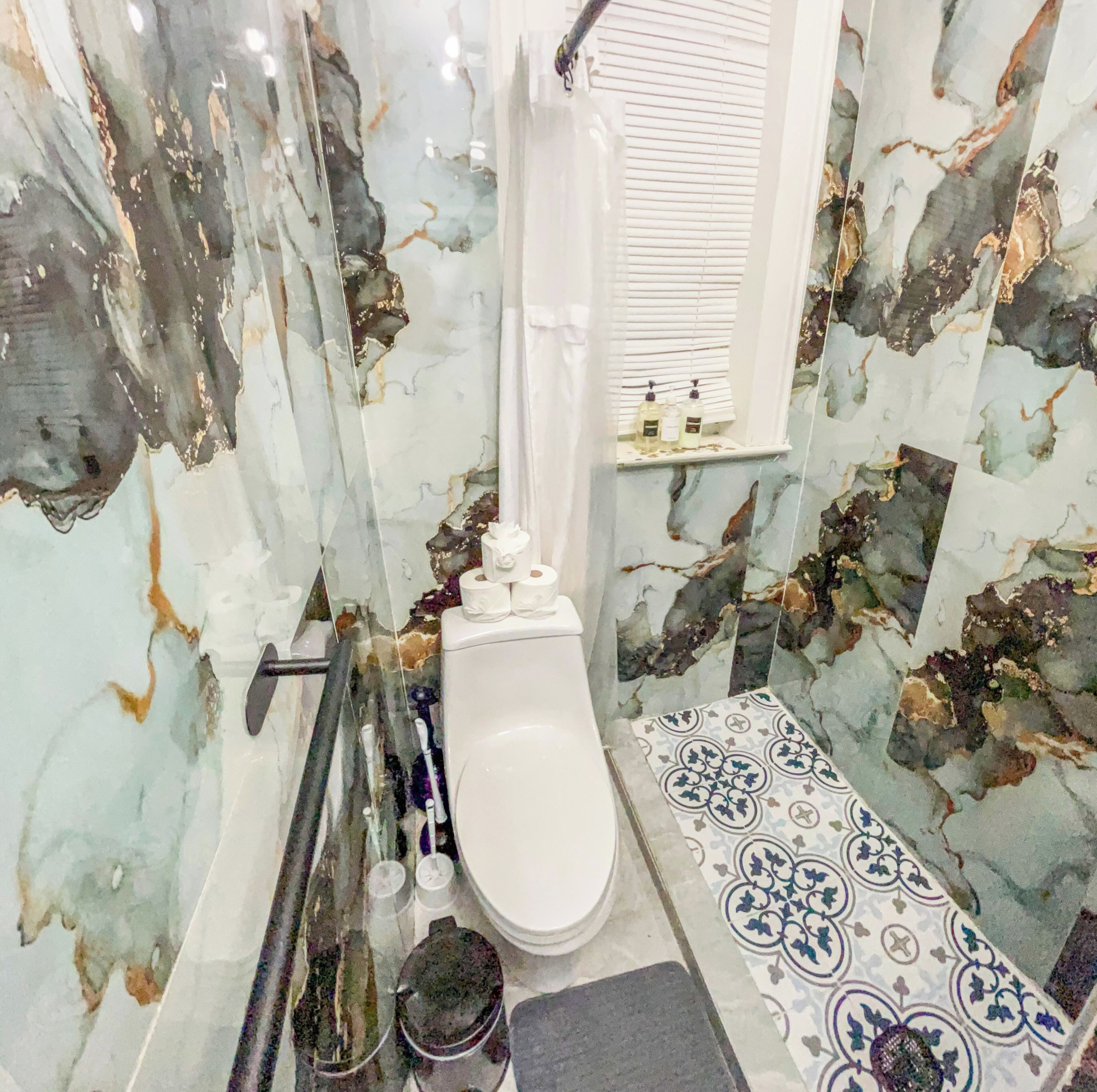 Une salle de bain avec des toilettes blanches, un espace douche et une petite étagère contenant des articles de toilette.