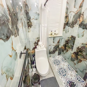 Une salle de bain avec des toilettes blanches, un espace douche et une petite étagère contenant des articles de toilette.