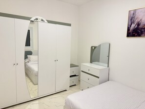Une chambre à coucher avec un lit, une armoire, une commode et un miroir.