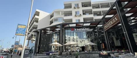 A modern building with a fitness center, outdoor seating, and a staircase leading to the entrance.
