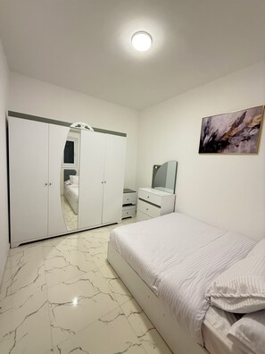 A bedroom with a bed, a wardrobe, a dresser, a mirror, and a painting on the wall. - Charming Apartment in the heart of Hurghada (Hurghada)