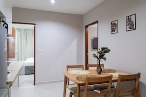 A dining area with a wooden table, chairs, and a vase with a plant. - The one Sky (Phuket)
