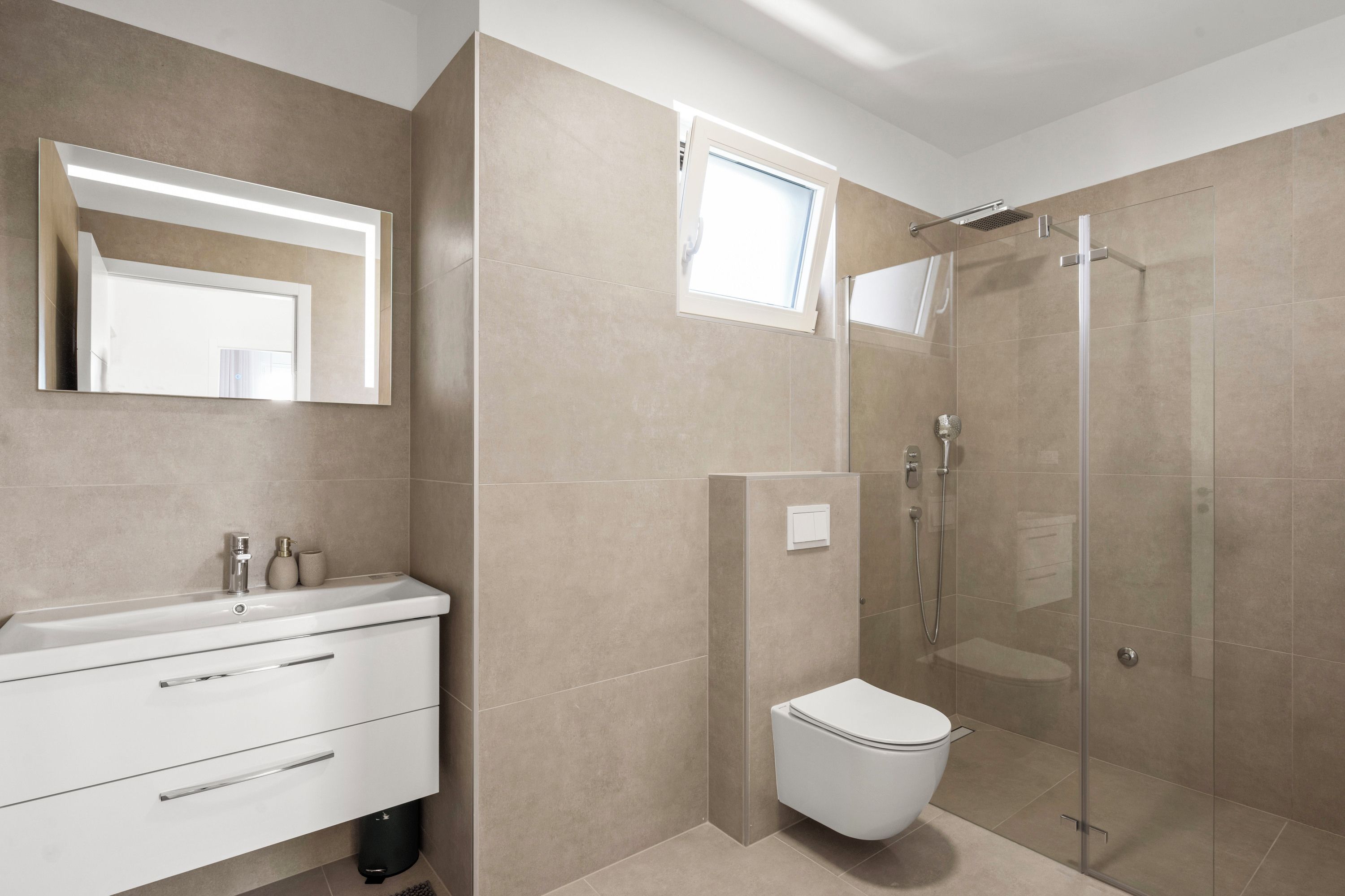 Une salle de bain moderne avec une douche à parois de verre, des toilettes et un meuble-lavabo avec un miroir.