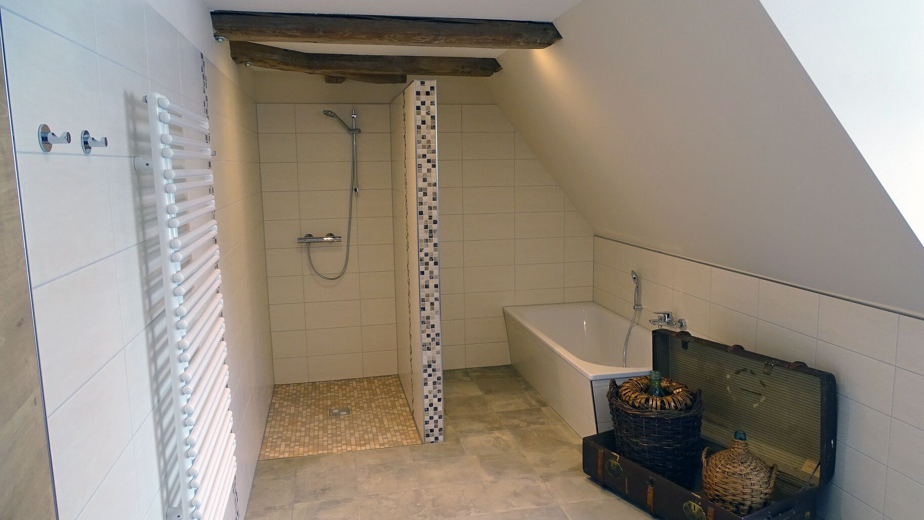 A small, sloped-roofed bathroom with a shower, a bathtub, and a radiator.