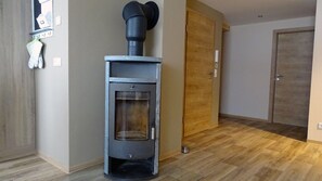 A modern interior with a wood-burning stove, a wooden door, and a light switch on the wall. - Idyllic Adlerhorst Vacation Rental – Farm Vacation & Open Fireplace (Bahretal)
