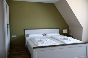 A bedroom with a bed, a nightstand, a lamp, and a power outlet on the wall. - Vrbo Property (Bahretal)