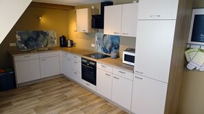 A compact kitchen with white cabinets, a microwave, a dishwasher, and a coffee maker. - Idyllic Adlerhorst Vacation Rental – Farm Vacation & Open Fireplace (Bahretal)