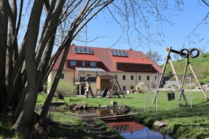 A house with a red roof, solar panels, and a small pond. - Idyllic Adlerhorst Vacation Rental – Farm Vacation & Open Fireplace (Bahretal)