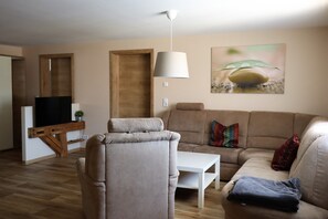 A living room with a sofa, a coffee table, a TV, and a painting on the wall. - Vrbo Property (Bahretal)