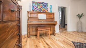 Ein Holzpiano mit Noten, eine Bank und ein farbenfrohes abstraktes Gemälde darüber.