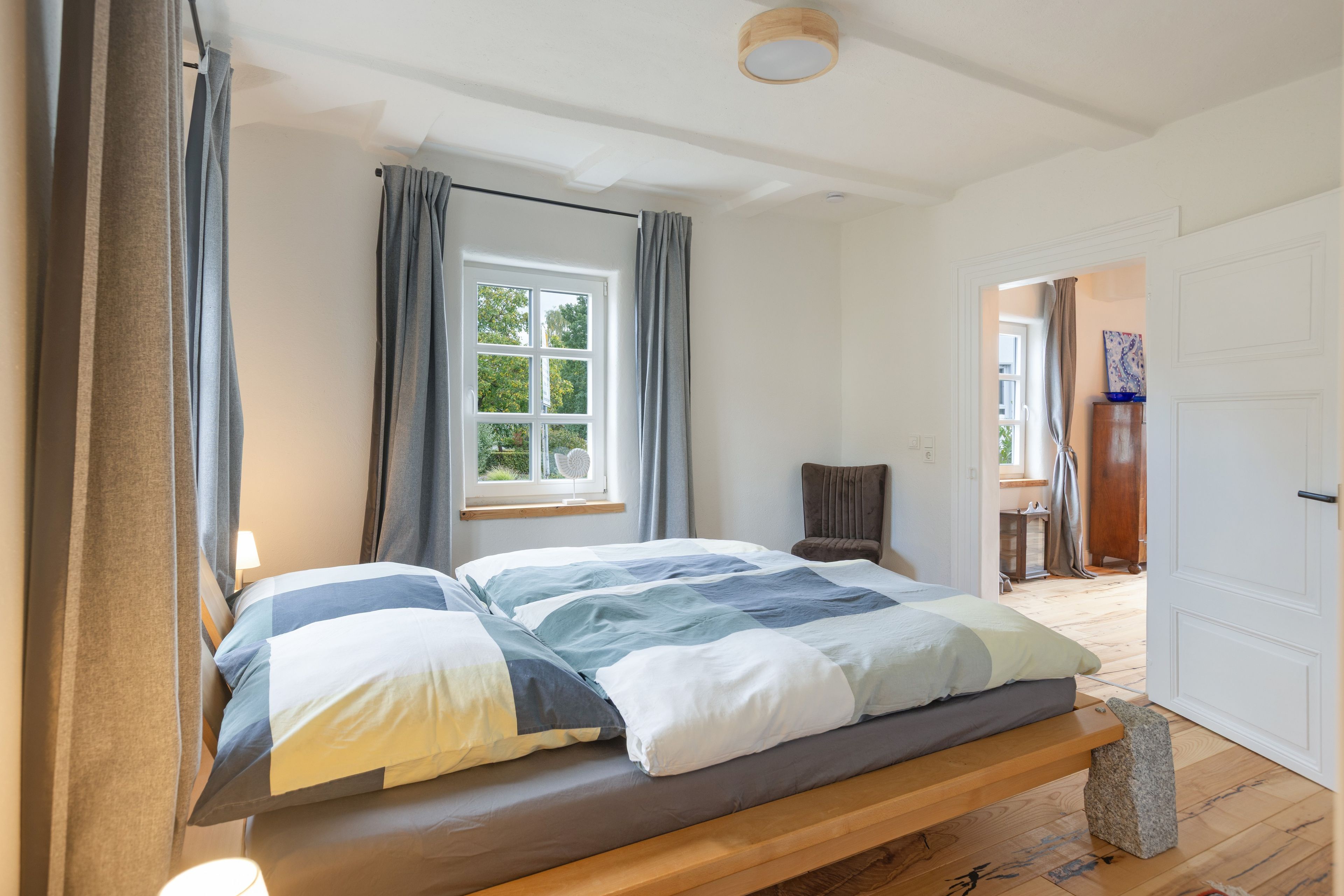 Een slaapkamer met een bed, een raam, een stoel en een deur.