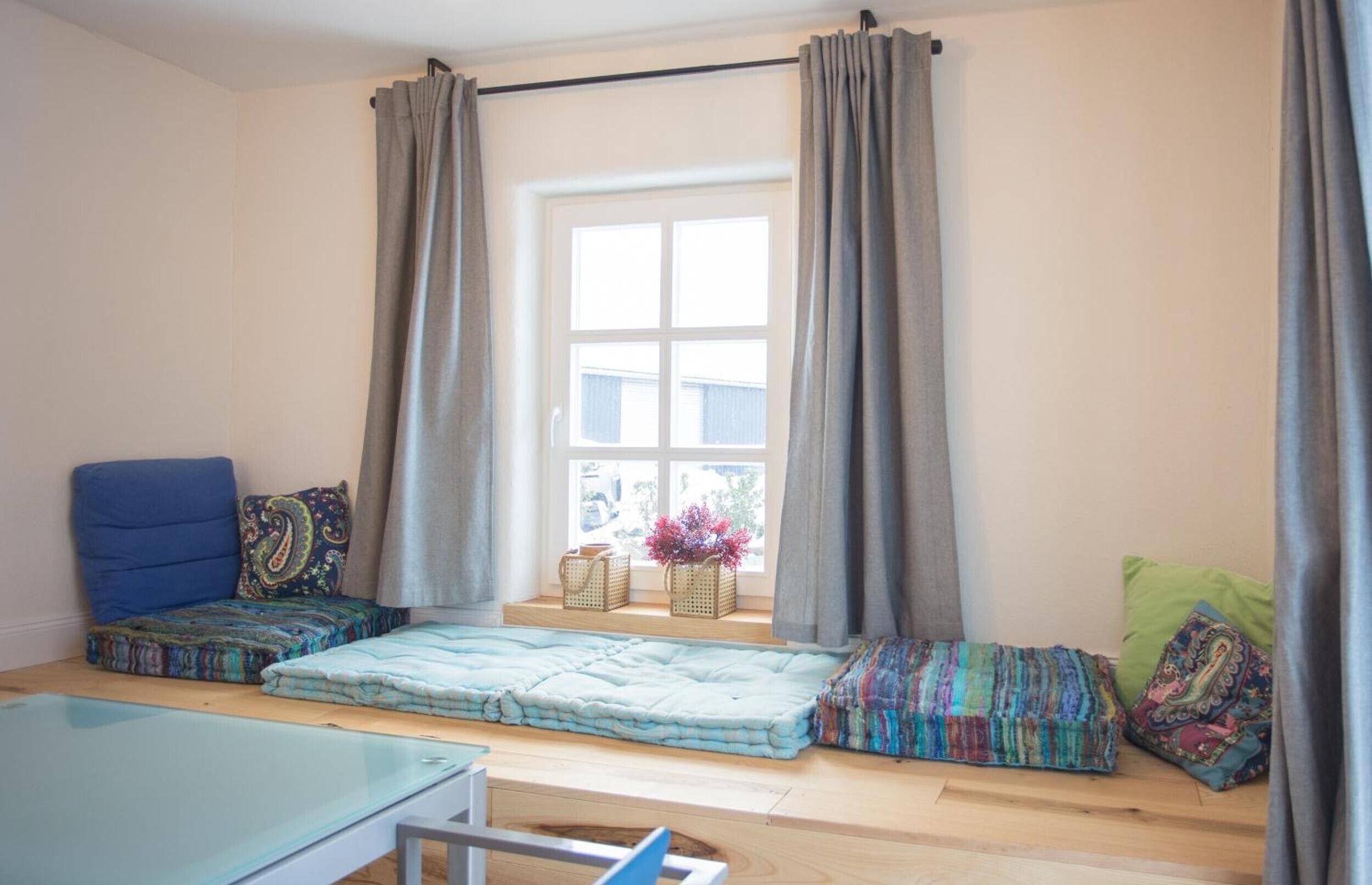 A cozy room with a bed, a blue chair, and a window with curtains.