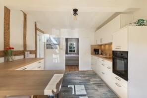 A modern kitchen with white cabinets, a wooden countertop, and a black oven.