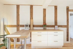 A kitchen with a wooden table, white cabinets, and exposed beams. - Apartment 'Denkmal Haus Hugo EG' with Private Terrace, Shared Garden and Wi-Fi (Medebach)