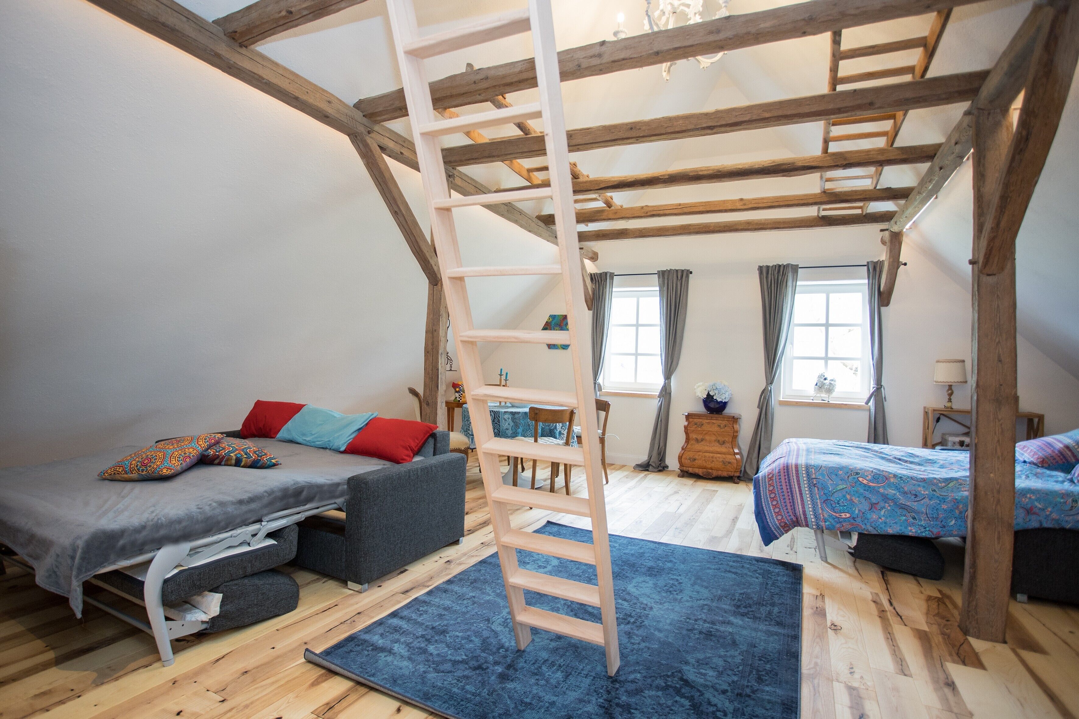 Een slaapkamer in loftstijl met een hoogslaper, een slaapbank en een bureau.