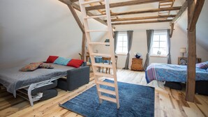 Une chambre de style « loft » avec un lit en mezzanine, un canapé et un bureau.