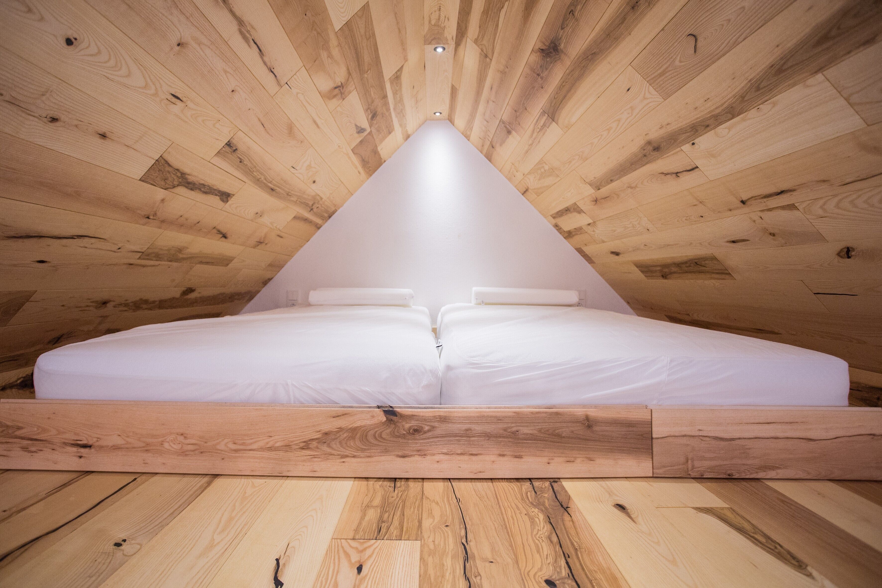 Eine dreieckige Decke mit Holzbalken und einer zentralen Lichtleuchte.
