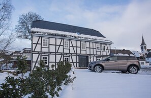 A traditional half-timbered house with a car parked in front, surrounded by snow. - Denkmal Haus Hugo Loft Apartment with Alpine Flair and Wi-Fi (Medebach)