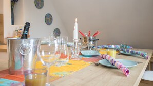 Une table à manger dressée avec différents types de verres, une bougie et une nappe colorée.