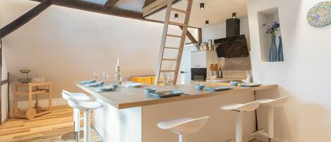 A modern kitchen with a central island, bar stools, and a wooden ceiling.