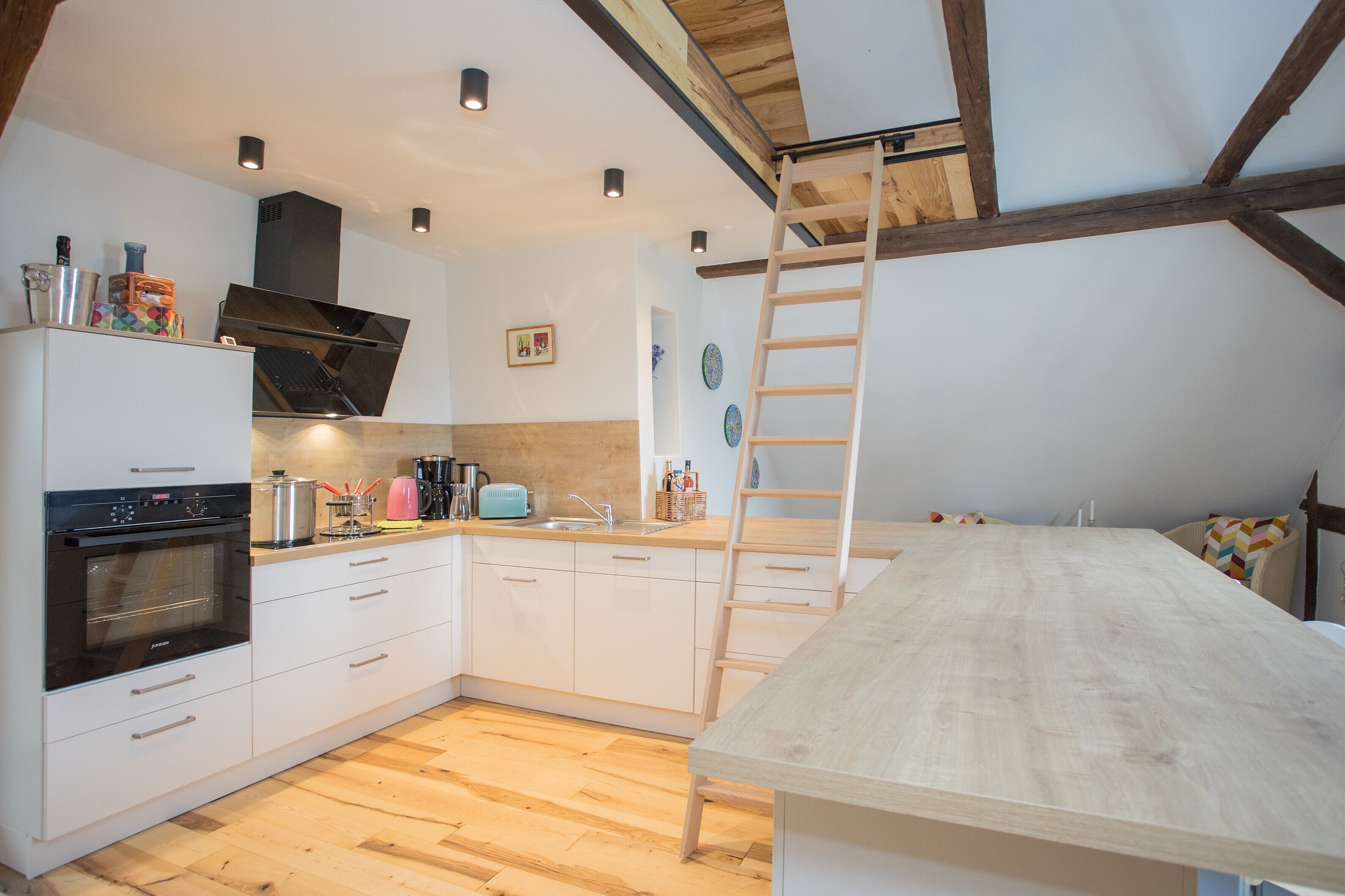 A kitchen with a wooden table, a built-in oven, and a ladder.