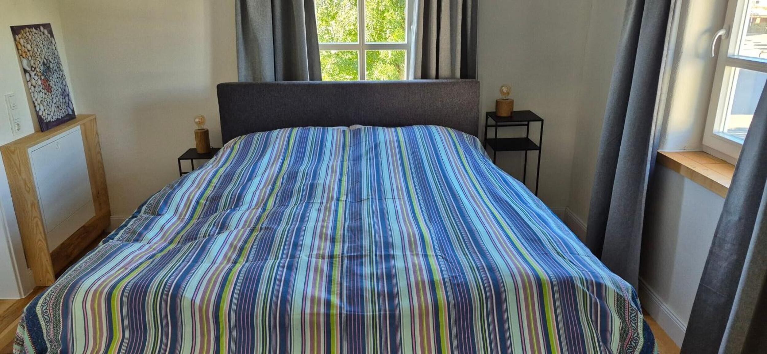 Een slaapkamer met een bed, een raam en een nachtkastje.