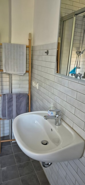 Ein Badezimmer mit einem weißen Waschbecken, einem Spiegel und einem Handtuchhalter.